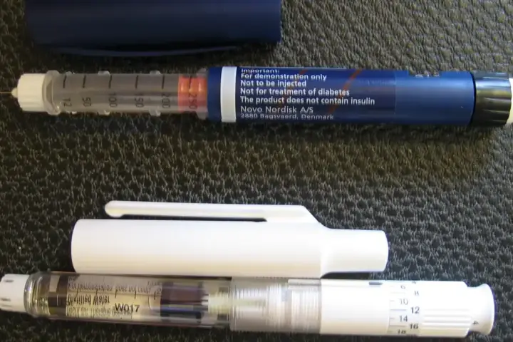 A medical subcutaneous injection pen resting horizontally on a clean surface.