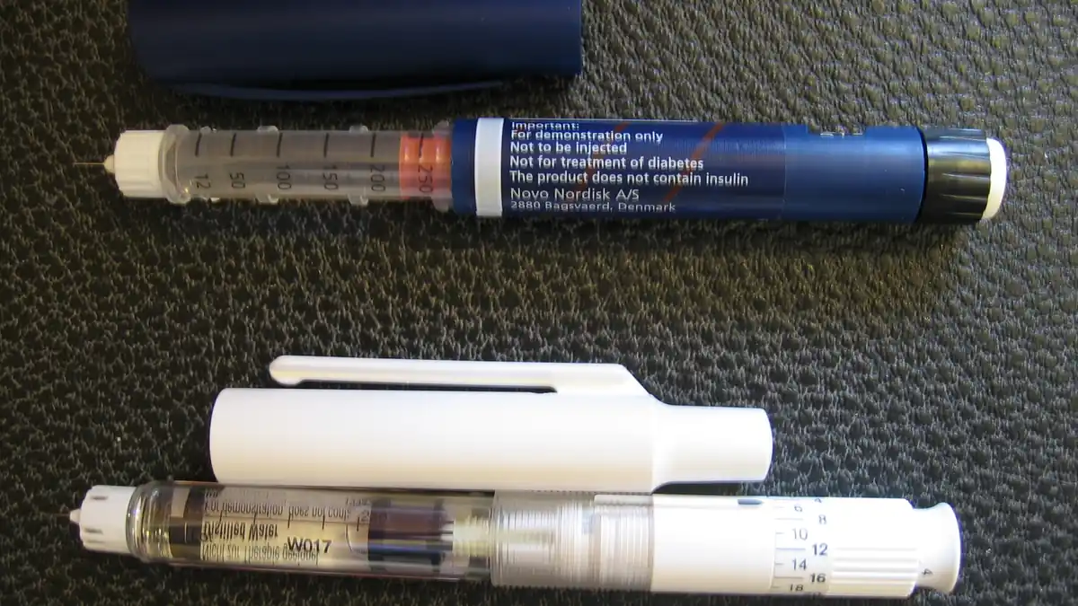 A medical subcutaneous injection pen resting horizontally on a clean surface.