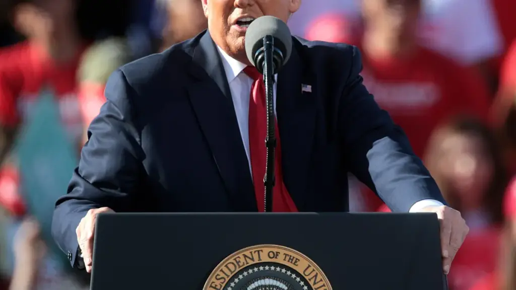 Former US President Donald Trump speaking into microphones at a podium during a political rally.