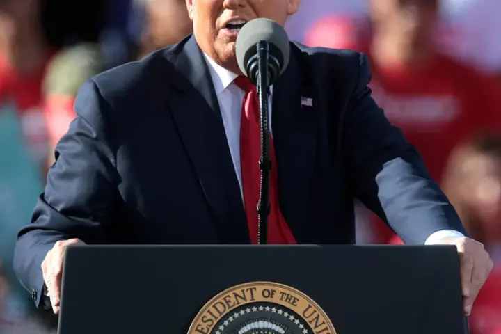 Former US President Donald Trump speaking into microphones at a podium during a political rally.