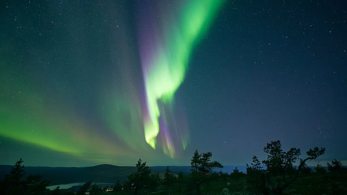 Bright green curtains of the aurora borealis glowing across a clear, dark night sky filled with stars.