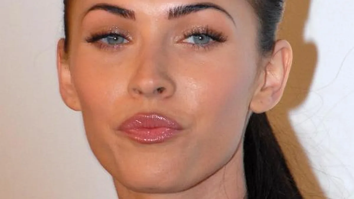 Close-up photographic portrait of actress Megan Fox facing forward at a red-carpet media appearance.