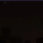 Night sky filled with stars and a sharp glowing trail of a meteor passing through the frame.