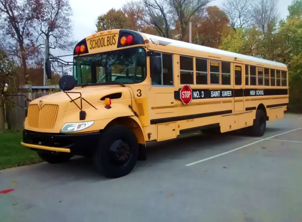 Yellow school bus at Saint Xavier High School, illustrating student transportation safety for intercity travel events.