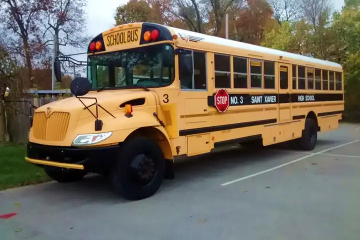 Yellow school bus at Saint Xavier High School, illustrating student transportation safety for intercity travel events.