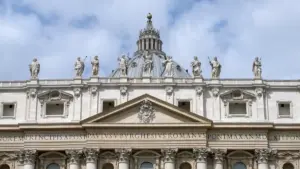 Wide exterior view of the facade and papal balcony of St. Peter’s Basilica overlooking St. Peter’s Square in Vatican City.