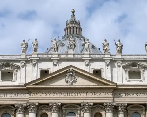 Wide exterior view of the facade and papal balcony of St. Peter’s Basilica overlooking St. Peter’s Square in Vatican City.