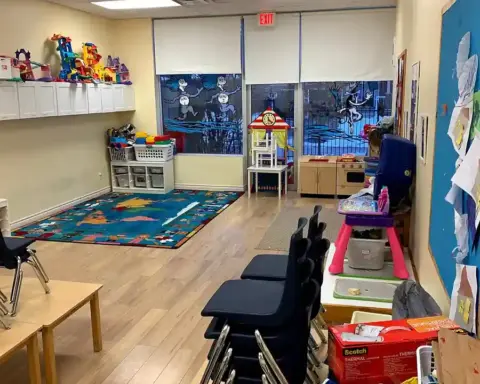 Clean and structured early childhood preschool classroom showing small activity tables, educational toys, and learning stations.