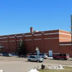Front entrance of a multistory brick urban public school building under daylight.