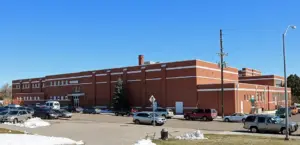 Front entrance of a multistory brick urban public school building under daylight.