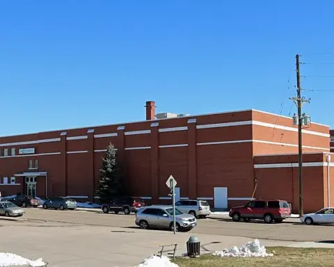 Front entrance of a multistory brick urban public school building under daylight.