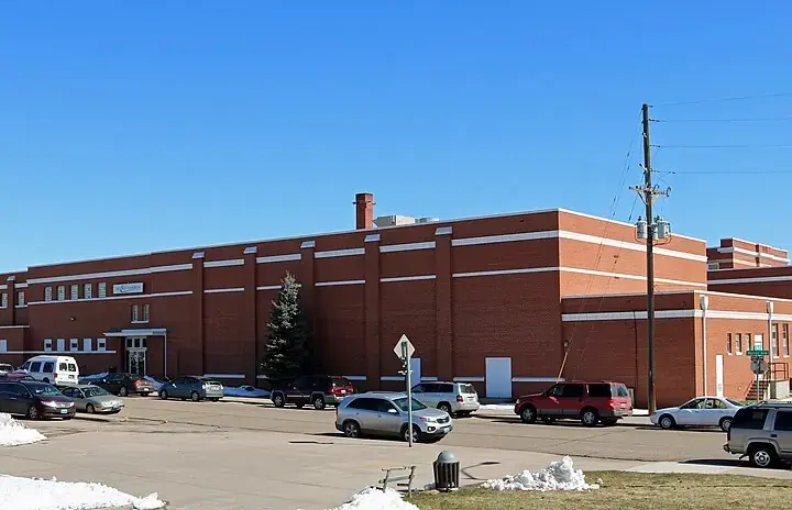 Front entrance of a multistory brick urban public school building under daylight.