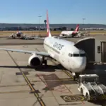 Red and white Qantas passenger aircraft on an Australian airport apron during daytime ground operations
