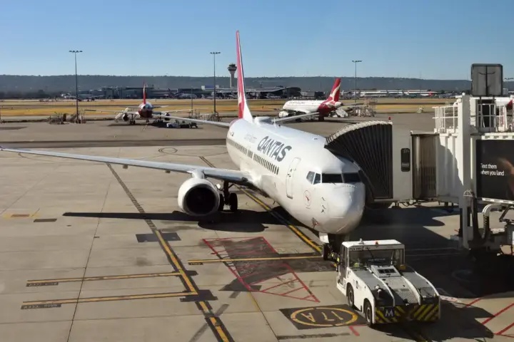 Red and white Qantas passenger aircraft on an Australian airport apron during daytime ground operations