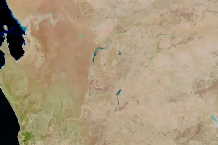 Satellite aerial view showing floodwaters inundating residential streets and suburban areas during severe weather event