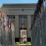 International flags line a government office plaza under clear skies.