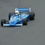 Vintage Formula racing car drives around a track during a motorsport event.