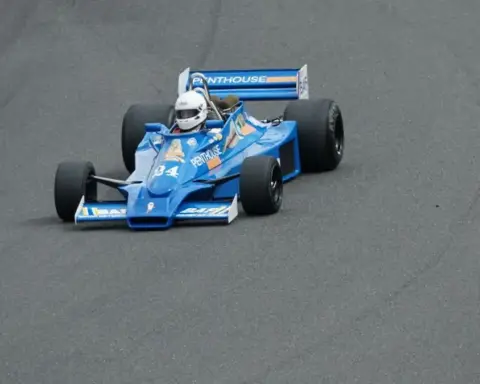 Vintage Formula racing car drives around a track during a motorsport event.