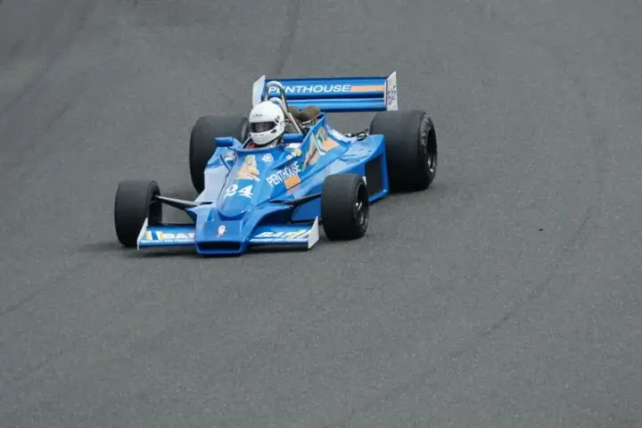 Vintage Formula racing car drives around a track during a motorsport event.