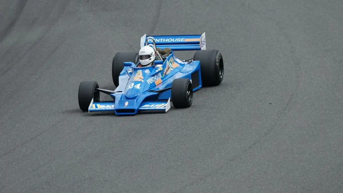 Vintage Formula racing car drives around a track during a motorsport event.