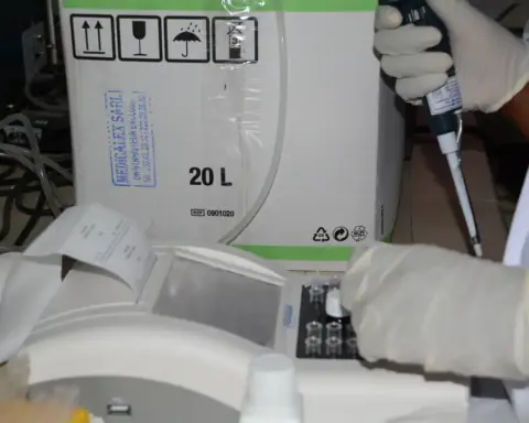 Clinical laboratory technicians in lab coats processing medical samples, representing research infrastructure for drug trials.