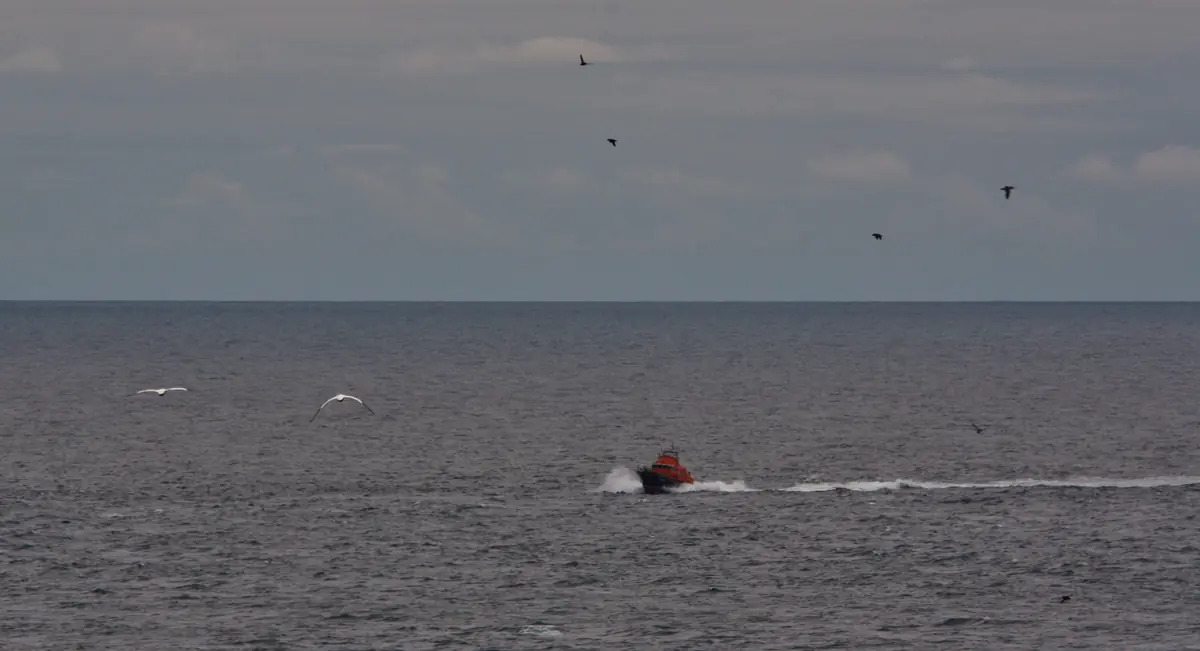 Royal National Lifeboat Institution Severn-class lifeboat navigating choppy coastal waters under grey skies.