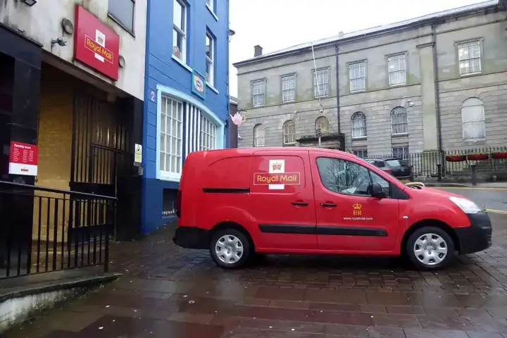 Red postal-delivery van parked on a UK street