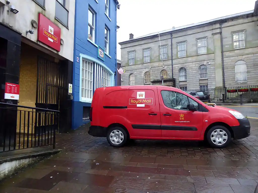 Red postal-delivery van parked on a UK street