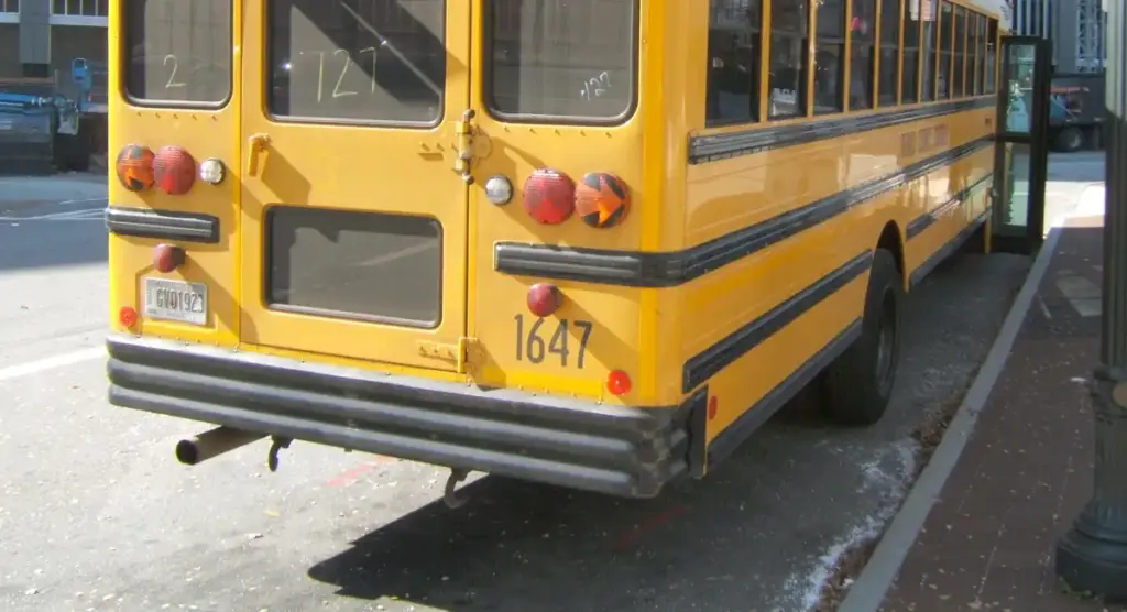 A yellow school bus parked beside a school entrance in Conyers, Georgia, representing school transportation safety after the Salem High School rollover crash.