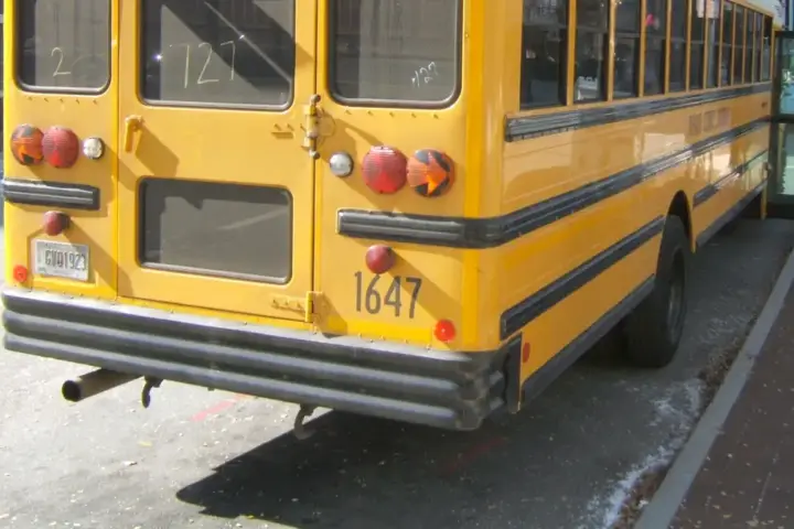 A yellow school bus parked beside a school entrance in Conyers, Georgia, representing school transportation safety after the Salem High School rollover crash.