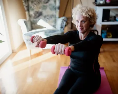 An older adult using elastic resistance bands to perform an upper-body strength exercise indoors.