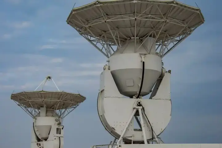 Large satellite dishes and launch infrastructure at SpaceX Starbase in Boca Chica adjacent to coastal Texas wildlife refuge wetlands.