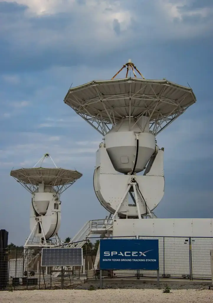 Large satellite dishes and launch infrastructure at SpaceX Starbase in Boca Chica adjacent to coastal Texas wildlife refuge wetlands.