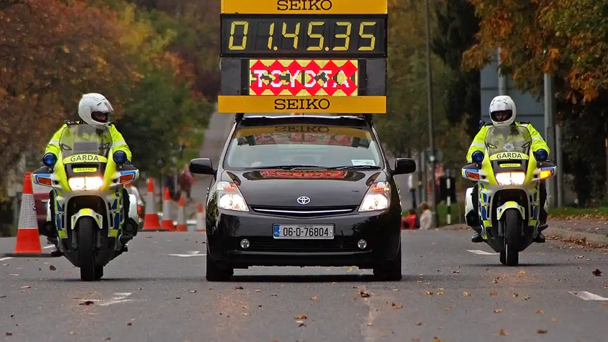 A dense pack of marathon runners racing along a closed city street in Dublin, Ireland.