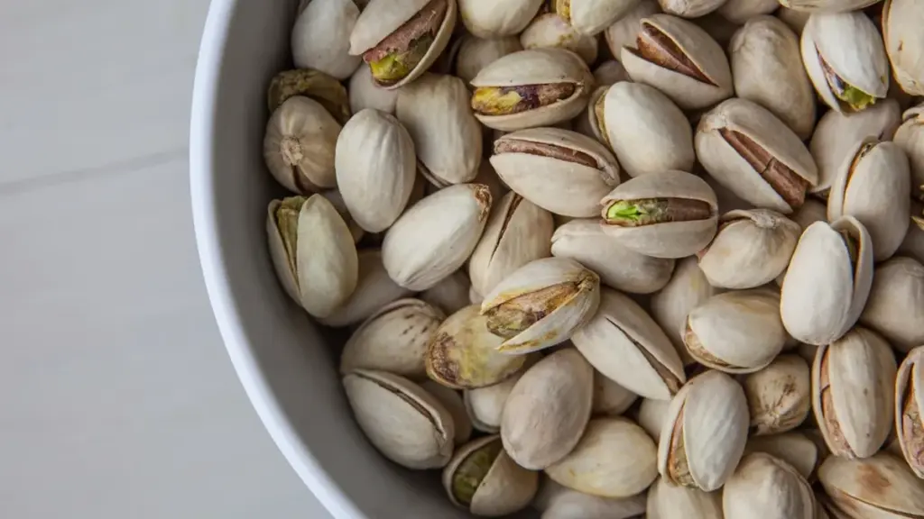 Close-up photograph of whole shelled pistachio nuts in bulk storage prior to commercial packaging and distribution.