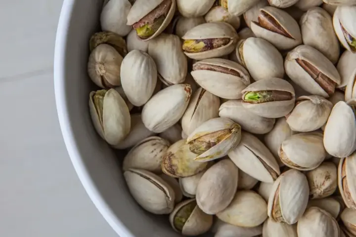 Close-up photograph of whole shelled pistachio nuts in bulk storage prior to commercial packaging and distribution.
