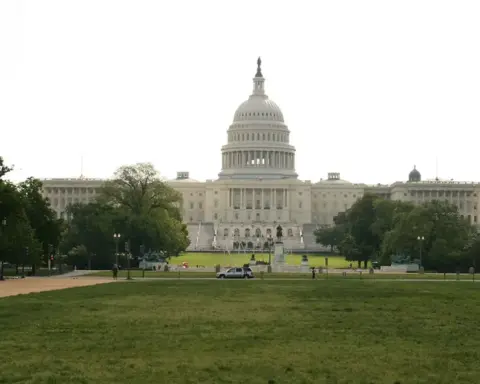 Full architectural photograph of the United States Capitol building under clear daylight, displaying the central dome and legislative wings.