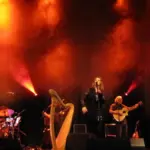 A band performs live on a small concert stage under coloured lighting.