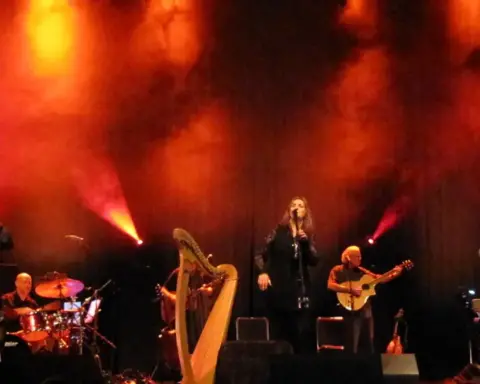 A band performs live on a small concert stage under coloured lighting.