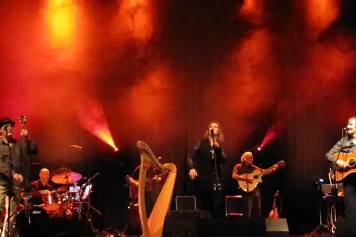 A band performs live on a small concert stage under coloured lighting.