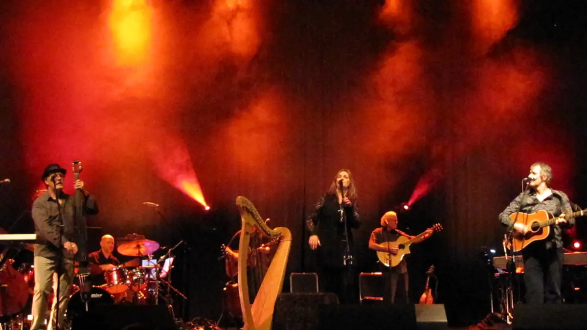 A band performs live on a small concert stage under coloured lighting.
