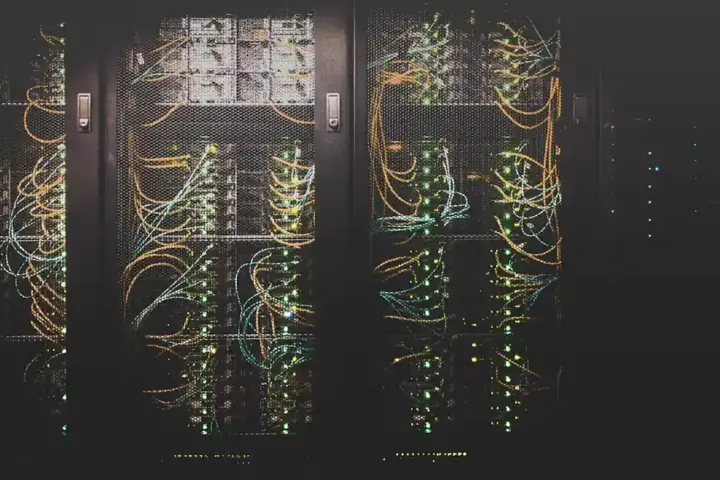 Rows of illuminated black enterprise computing server racks line a server room with blue and white indicator lights.