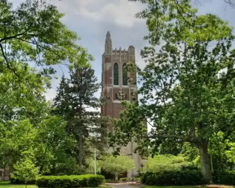Brick clock and bell tower surrounded by trees and pathways on the Michigan State University campus in East Lansing.