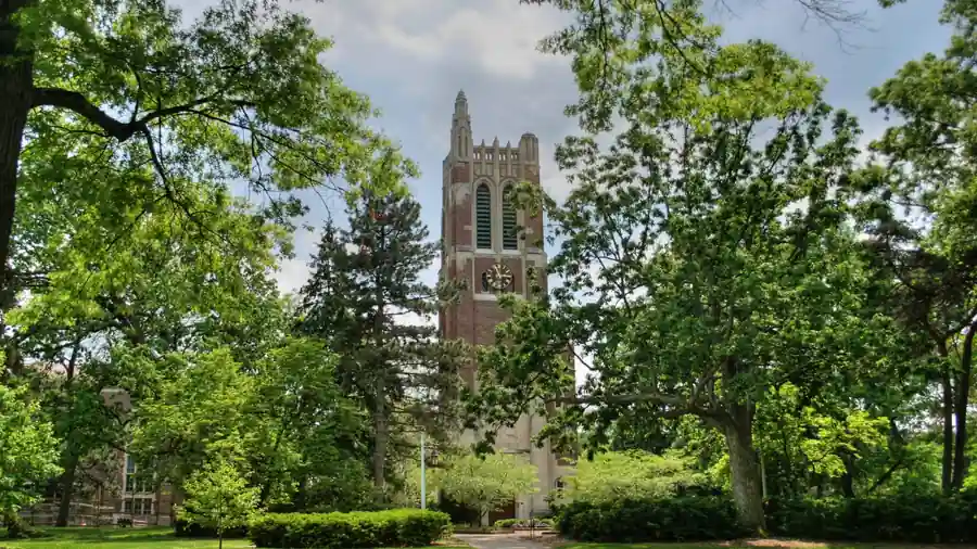 Brick clock and bell tower surrounded by trees and pathways on the Michigan State University campus in East Lansing.