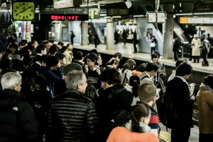 Commuters walking through an interior transit concourse of Shinjuku Station in Tokyo