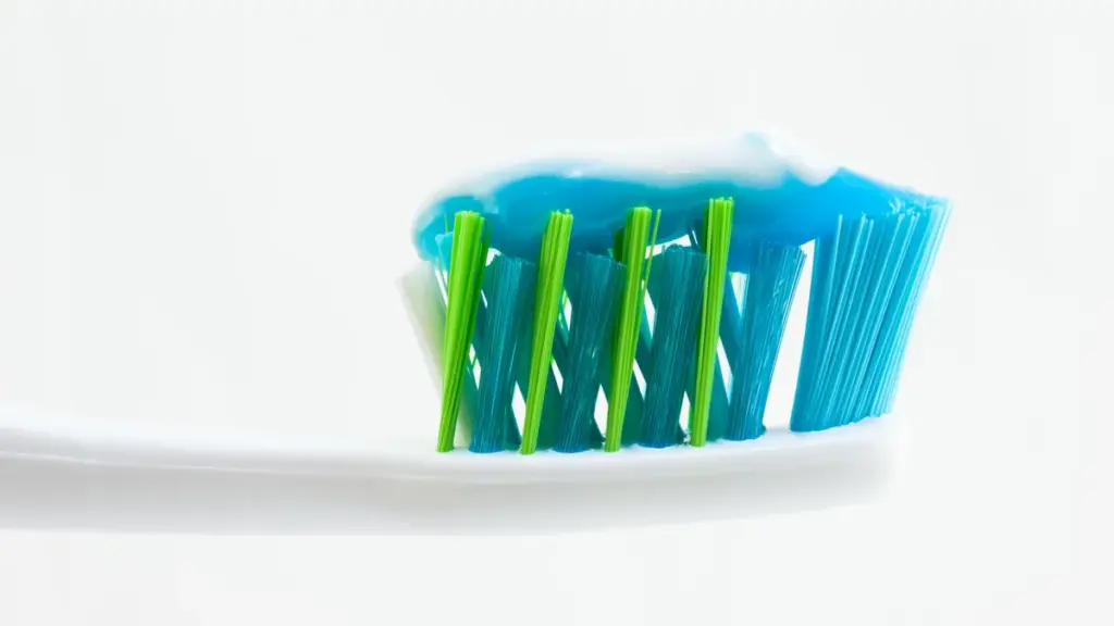 Close-up of an unbranded toothbrush with blue and white toothpaste applied to the bristles