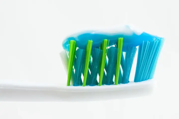 Close-up of an unbranded toothbrush with blue and white toothpaste applied to the bristles