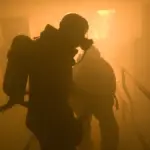 Sailors in protective gear spray aqueous film-forming foam during a firefighting training exercise