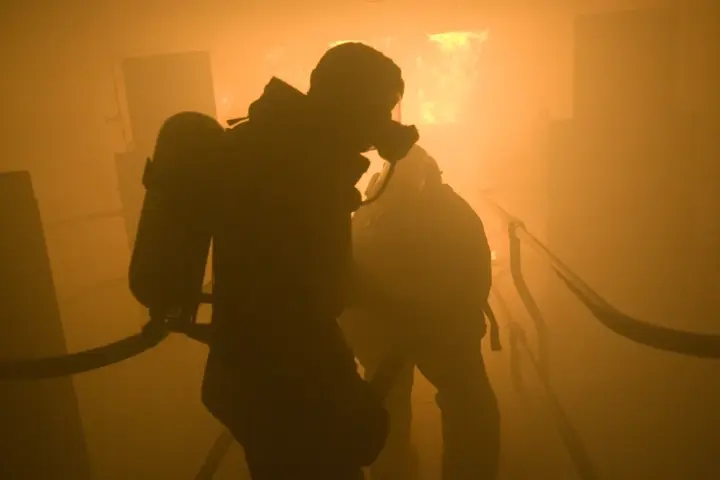 Sailors in protective gear spray aqueous film-forming foam during a firefighting training exercise