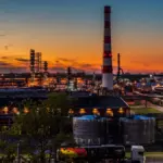 Industrial distillation columns, piping networks, and refining towers processing crude oil into refined diesel and fuel products.